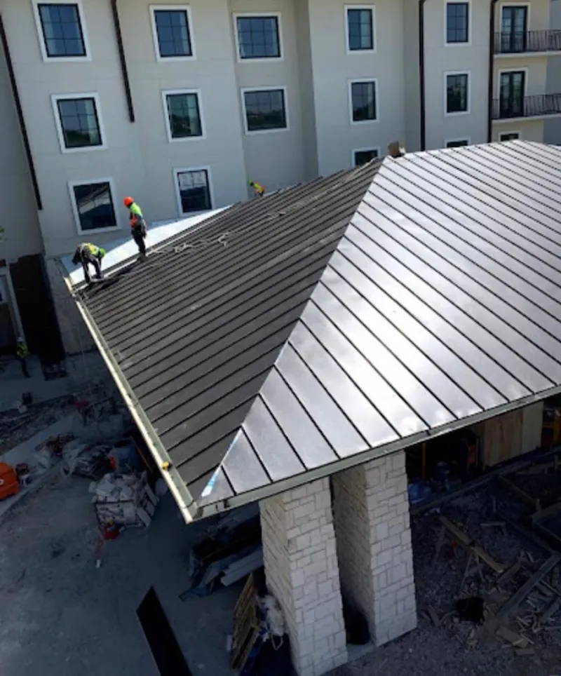 Crew installing standing seam metal roof panels on a commercial project in Milan